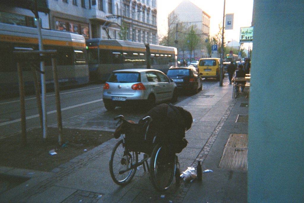 Fotografie eines Rollstuhlfahrers, eingeschlafen mit Bier auf dem Boden.